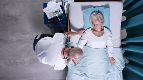 Top View Of Doctor With Stethoscope Examining Patient In Bed In Hospital. Copy Space.