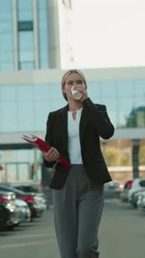 Professional Woman Walking with Coffee and Folder in Urban Office Parking Lot
