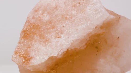Extremely close view of pink salt rock sample. Rotating completely. Looping