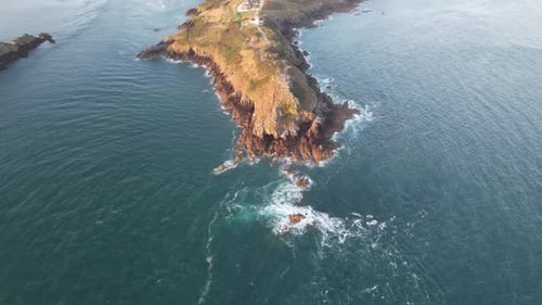 Aerial view of rocky cliffs and ocean at sunrise, France.