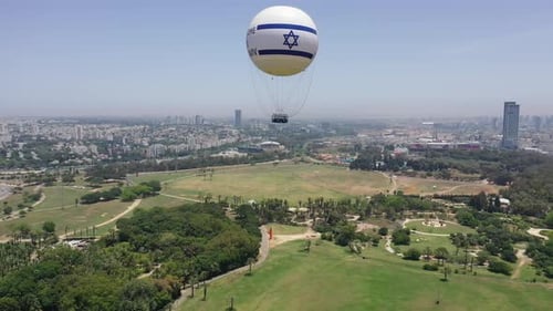 Aerial Shot Of Hot Air Balloon Descending Over Yarkon Park Against Sky In City