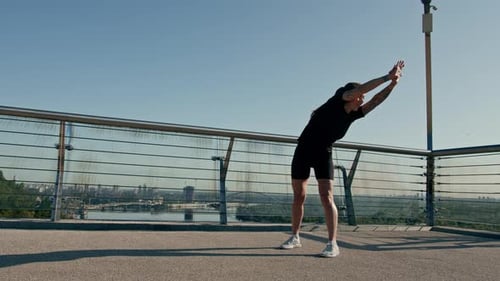 Fitness young sportswoman girl in the morning doing warm-up exercises before training on the street