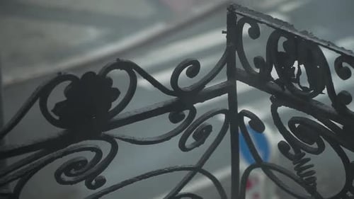 Old school metal balcony railing with decoration - spirals and leaves, cars in a background