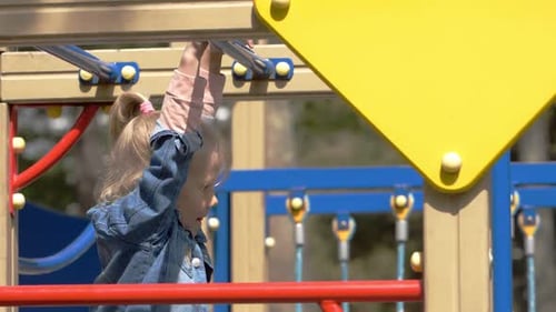 cute happy girl hanging from a monkey bar in a playground