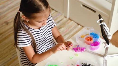 Girl Creating Rubber Band Bracelets at Home