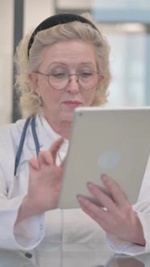 Doctora sénior que usa una tableta en la clínica, vídeo vertical