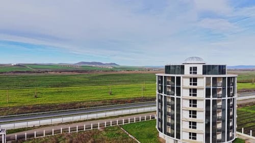 Weite grüne Felder und moderne Gebäude unter blauem Himmel