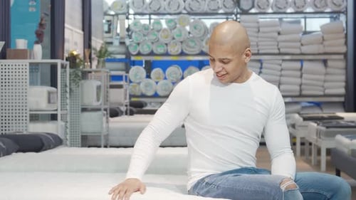 Cheerful Man Testing a Comfortable Mattress at a Furniture Store