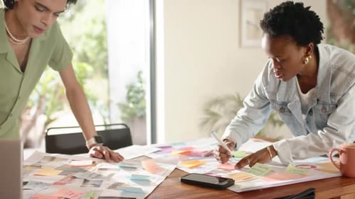 Une équipe diversifiée se penche sur un plan au bureau, un homme pointant du doigt exhortant une femme à écrire avec un marqueur pour le projet