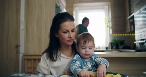 Mother Feeds Infant Breakfast at Kitchen Table