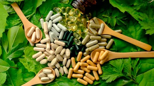 Assorted Pills and Capsules on Green Leaves