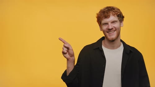 Ginger Guy Pointing At Copy Space on Yellow Background