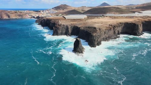 Turquoise water waves crashing on the rocky cliff of Risco Partido in Gran Canaria