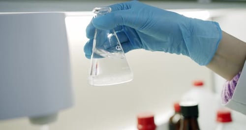 Scientist Examining Clear Liquid in Glass Flask