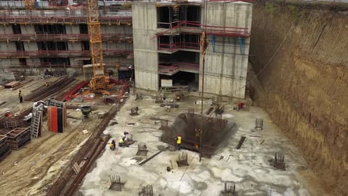 Aerial view of construction workers assembling large rebar structures and foundation piles at the ba