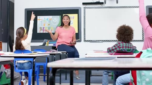In school, teacher engaging with students raising hands in classroom discussion