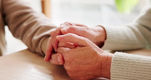 Holding hands, bonding and senior couple by table for love, empathy or forgiveness in marriage