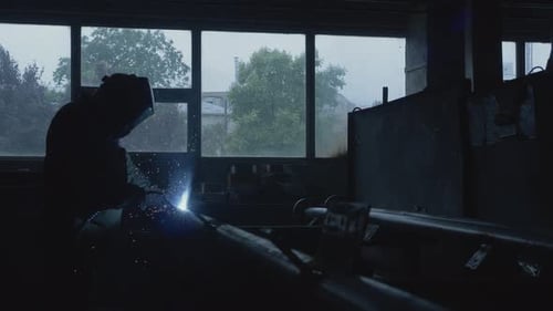 Silhouette of Welder Working on Metal in Factory