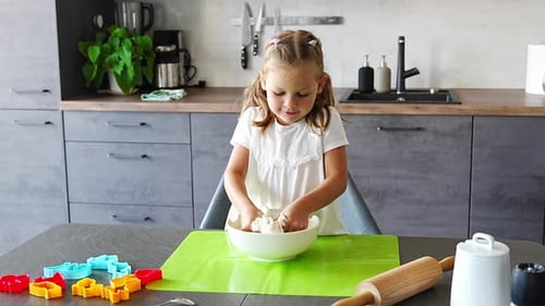 Little Girl Mixes Dough in Kitchen Bowl