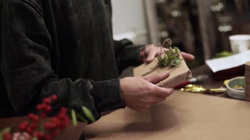 Hands Wrapping a Present with Brown Paper and Twine