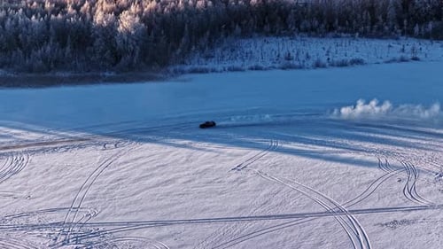 Car drifting on ice of frozen lake with winter snowy forest backdrop
