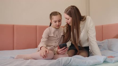 Woman and Child Using Mobile Phone on Bed