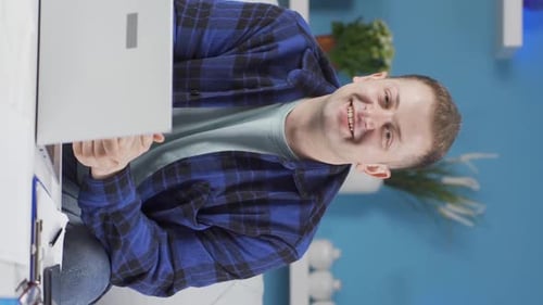 Vertical video of Home office worker man looking at camera with excitement and feeling happy.