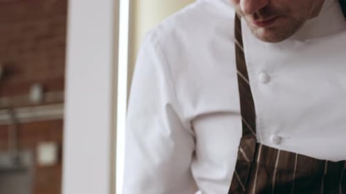 Professional Focused Chef Carefully Sprinkling Green Herbs Onto a Plate in Interior