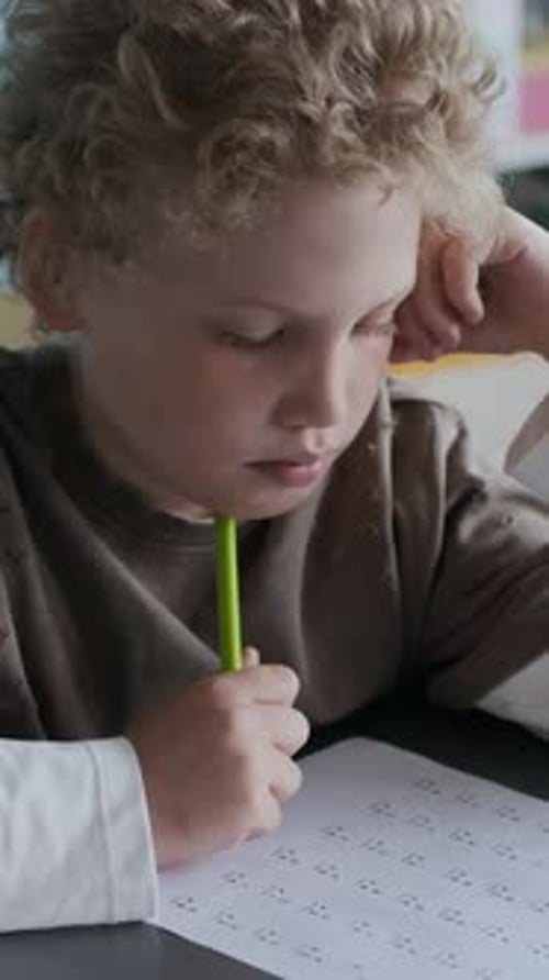 Vertical of Focused Student Working on Worksheet in Classroom