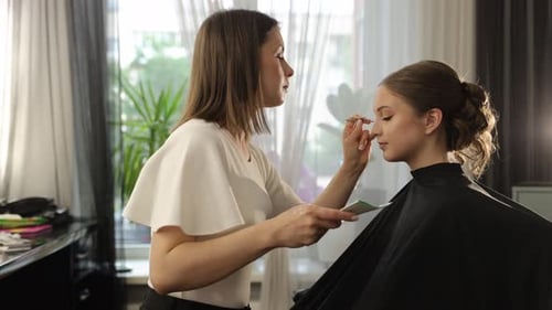 Makeup Artist Applies Makeup to a Client in a Bright Studio Setting Showcasing Beauty Techniques