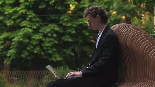 Kaukasischer junger Geschäftsmann, Freiberufler, der in der Pause mit Laptop im Freien arbeitet, männlicher Büroangestellter