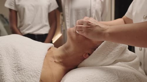 Mature Woman Receiving Relaxing Facial Cleansing Treatment at Spa