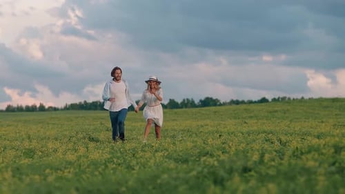 Countryside Cheerful Young Couple in Nature Man and a Woman are Running Through a Field of Rapeseed