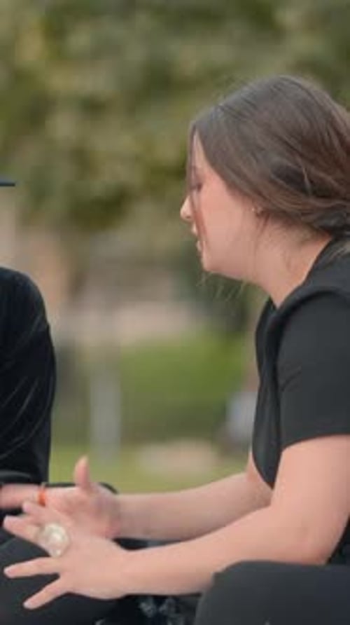 Une fille aux cheveux roses prend des notes dans un bloc-notes pendant que son amie lui dicte un gros plan statique