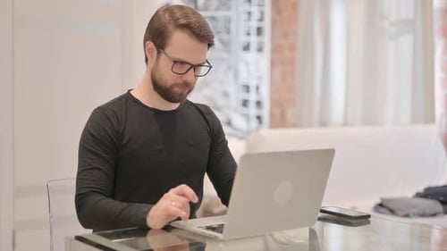 Man Celebrating Success with Laptop Indoors