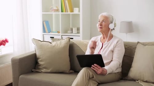 Happy Senior Woman with Tablet Pc Computer and Headphones Listening to Music