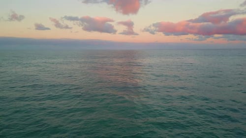 Drone Soft Ocean Sunset Bringing Pink Hue to Clouds Over Calm Tranquil Ocean