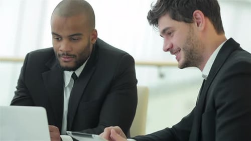 Smiling Successful Businessmen Sitting at Table in Office