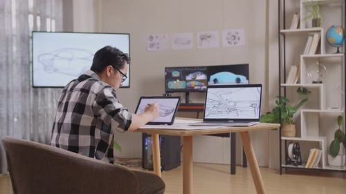 Side View Of Male Drawing New Car Design Concept On A Tablet In The Studio With Tv And Computer