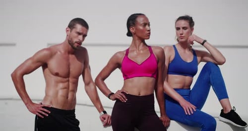 Vídeo em 4K de três jovens esportistas bonitos posando juntos ao ar livre