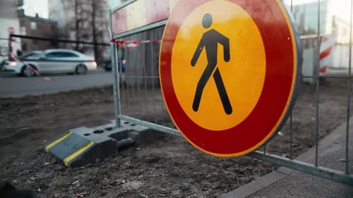 Verkehrszeichen in Gelb und Rot mit dem Symbol einer Person innerhalb eines Kreises, der an einem Zaun befestigt ist