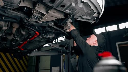 an Auto Mechanic at a Service Station is Trying to Remove the Base on Which the Wheel Held
