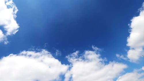 Light white clouds floating quickly in the bright blue skies. Fluffy clouds reflecting the rays