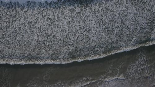 Top-down View Of White Foamy Waves Rolling At The Beach Shore. - aerial