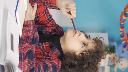 Child Writes in Notebook at Colorful Desk Indoors