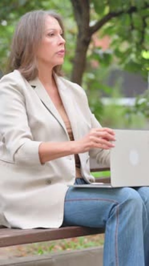 Mulher idosa fechando o laptop e saindo do banco ao ar livre