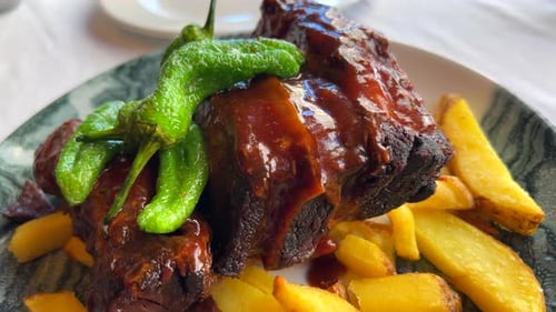 Delicious bbq pork ribs with green Spanish padron peppers and french fries, bbq sauce on grilled