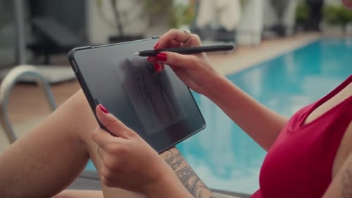 Hands of Woman Drawing on Tablet PC while Resting near Swimming Pool