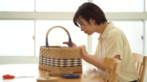Young Adult Weaving Basket at Table Indoors