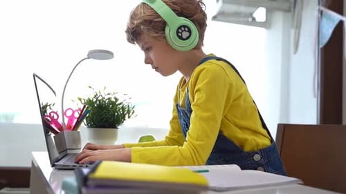 Boy Working on Laptop at Desk With Headphones